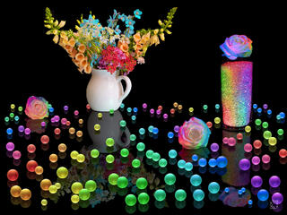 A fine art light painting photograph on a black reflective background featuring dozens of glowing neon orbs in blue, green, yellow, orange, pink, and purple